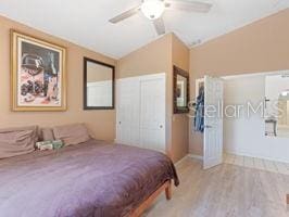 bedroom featuring light wood-type flooring, vaulted ceiling, and ceiling fan