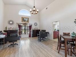 home office featuring an inviting chandelier, hardwood / wood-style flooring, and high vaulted ceiling