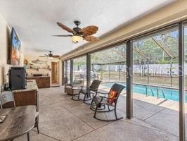 interior space featuring a fenced in pool, glass enclosure, and ceiling fan