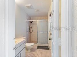 bathroom featuring a shower with door, vanity, and toilet