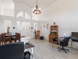 interior space with a notable chandelier, high vaulted ceiling, and light hardwood / wood-style flooring