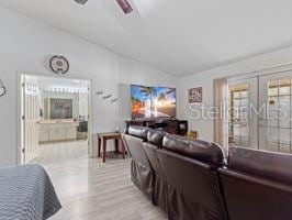 living room with french doors, light hardwood / wood-style floors, ceiling fan, and lofted ceiling