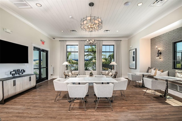 dining room with crown molding, a chandelier, brick wall, and dark wood-type flooring