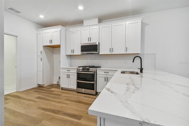 kitchen featuring sink, appliances with stainless steel finishes, light wood-type flooring, and white cabinetry