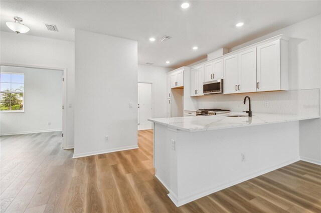 kitchen featuring kitchen peninsula, sink, white cabinets, and light wood-type flooring