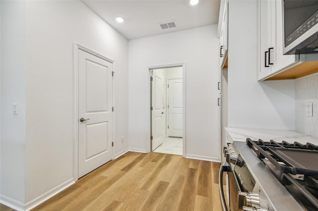 kitchen featuring appliances with stainless steel finishes, light hardwood / wood-style flooring, and white cabinets