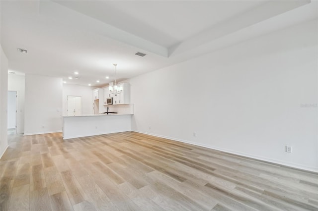 unfurnished living room with a notable chandelier and light hardwood / wood-style flooring