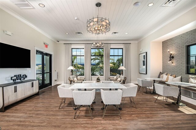 dining space with brick wall, a chandelier, hardwood / wood-style flooring, and crown molding