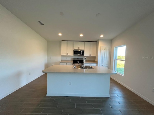 kitchen featuring a center island with sink, white cabinetry, sink, and appliances with stainless steel finishes