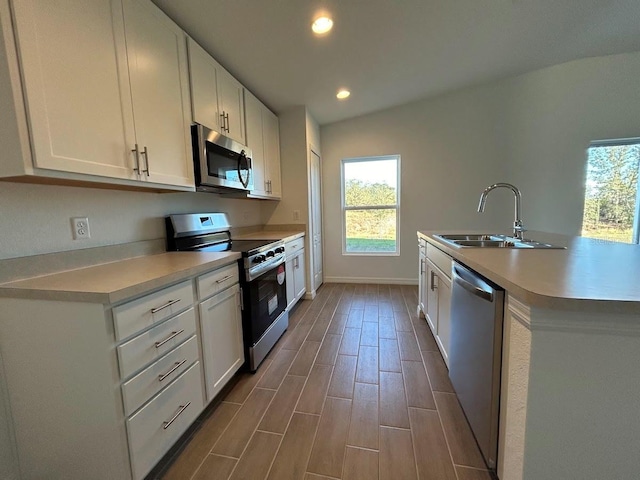 kitchen with wood-type flooring, appliances with stainless steel finishes, white cabinetry, and sink