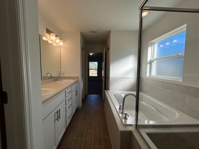 bathroom with vanity, tiled bath, and a wealth of natural light