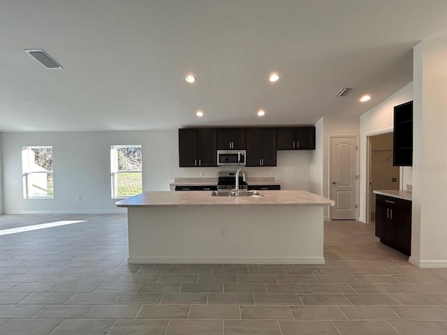 kitchen featuring sink, stainless steel appliances, lofted ceiling, a center island with sink, and light tile patterned floors