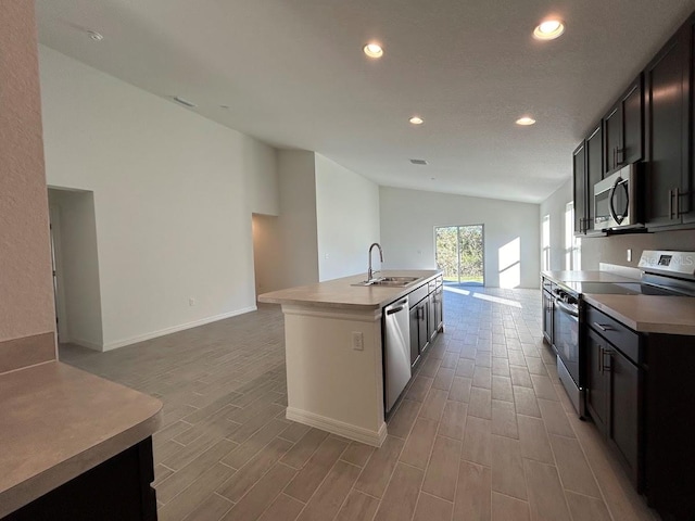 kitchen featuring stainless steel appliances, sink, light hardwood / wood-style floors, lofted ceiling, and an island with sink