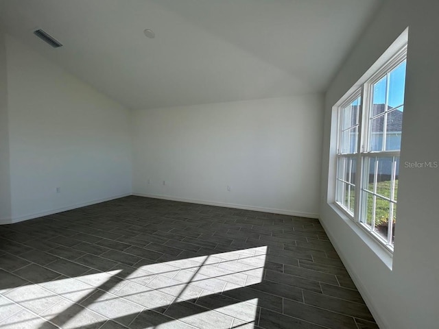 unfurnished room featuring a wealth of natural light, dark hardwood / wood-style flooring, and lofted ceiling