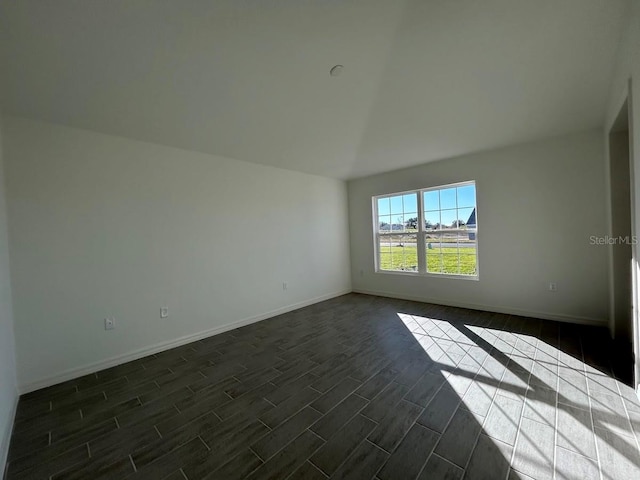 empty room with dark hardwood / wood-style floors and lofted ceiling