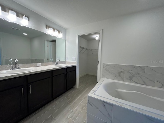 bathroom featuring wood-type flooring, vanity, and tiled tub