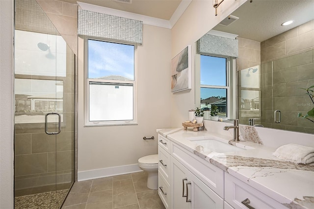 bathroom featuring vanity, a shower with shower door, a healthy amount of sunlight, and toilet