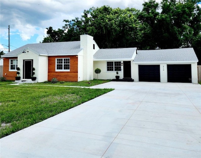 ranch-style home with a front yard, a garage, driveway, and a chimney