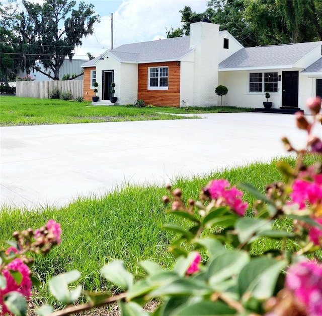 view of front facade with a front yard, a chimney, and fence