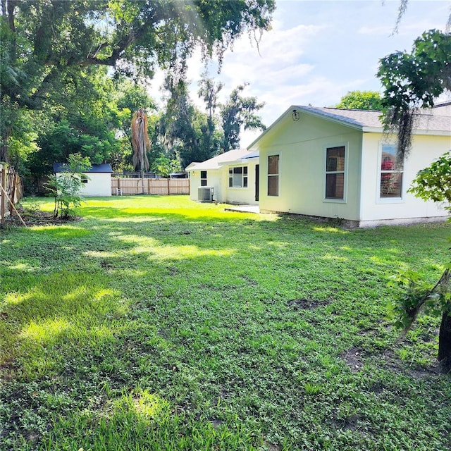 view of yard with an outbuilding, a shed, central AC, and a fenced backyard