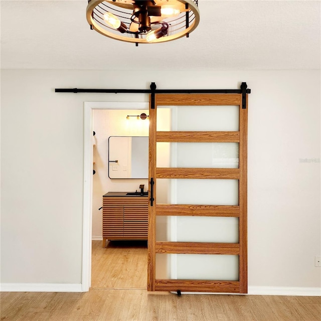 stairway featuring baseboards, a barn door, and wood finished floors