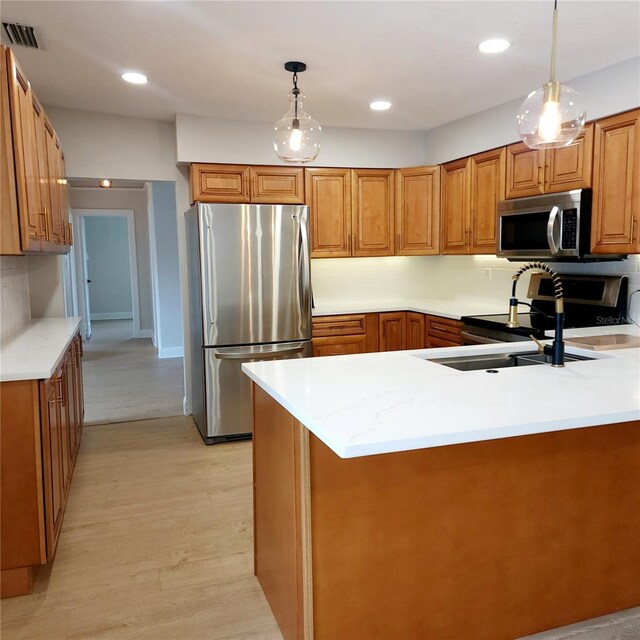 kitchen featuring sink, hanging light fixtures, light wood-type flooring, kitchen peninsula, and stainless steel appliances