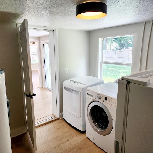 washroom with plenty of natural light, washer and dryer, a textured ceiling, and light wood-type flooring