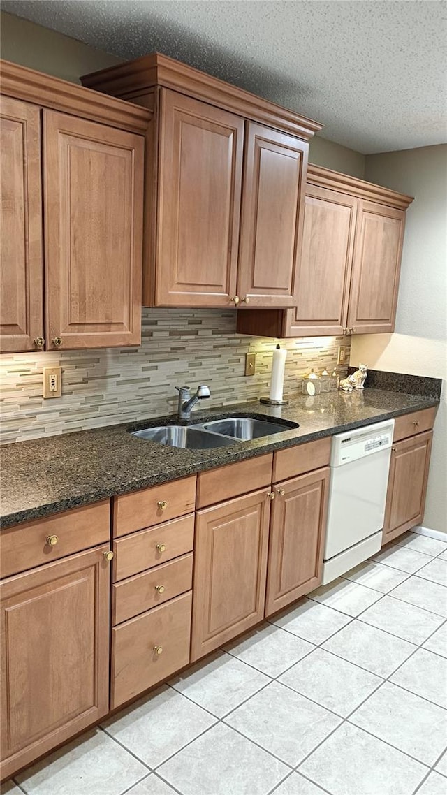 kitchen with sink, dark stone countertops, white dishwasher, a textured ceiling, and light tile patterned floors