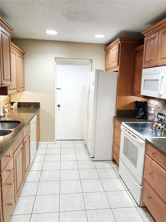 kitchen with sink, white appliances, a textured ceiling, and light tile patterned floors