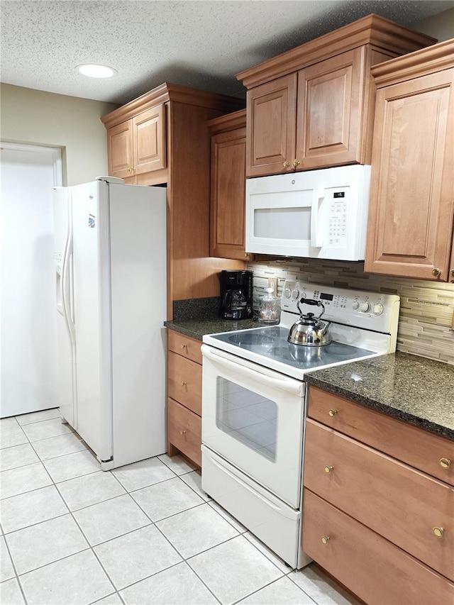 kitchen featuring tasteful backsplash, a textured ceiling, light tile patterned floors, and white appliances