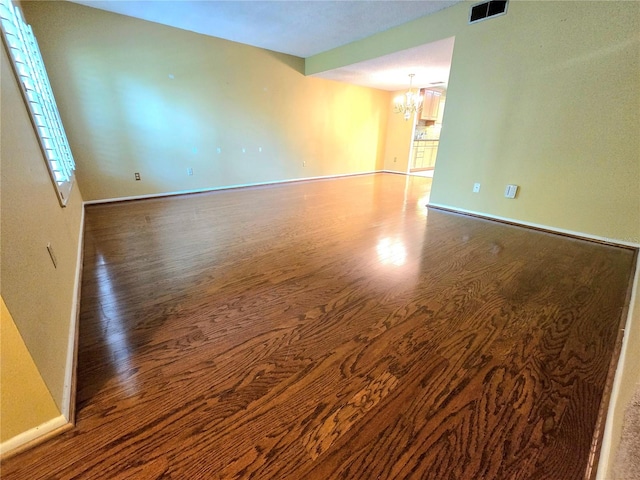 spare room featuring hardwood / wood-style floors and an inviting chandelier