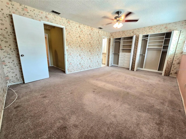 unfurnished bedroom featuring carpet, a textured ceiling, and ceiling fan