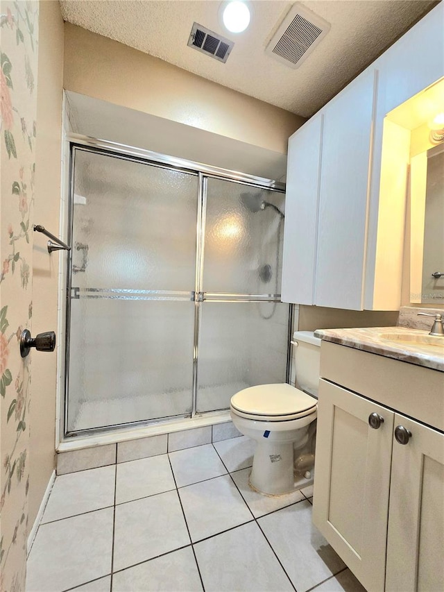 bathroom with a textured ceiling, vanity, a shower with door, tile patterned flooring, and toilet