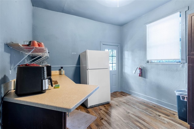 kitchen with white fridge, light wood-type flooring, and kitchen peninsula