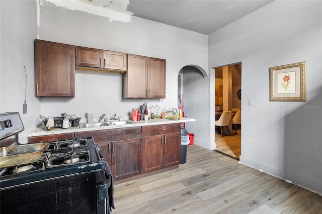 kitchen with black gas stove, light wood-type flooring, and sink