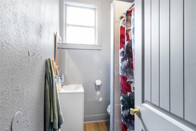 bathroom with wood-type flooring, vanity, toilet, and walk in shower