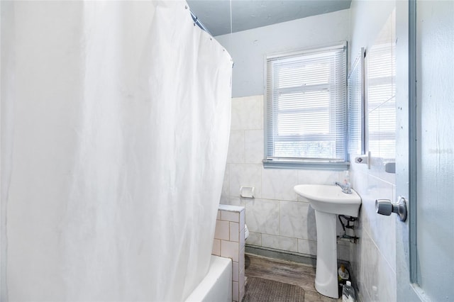 bathroom featuring tile walls, hardwood / wood-style floors, shower / bath combo, and sink