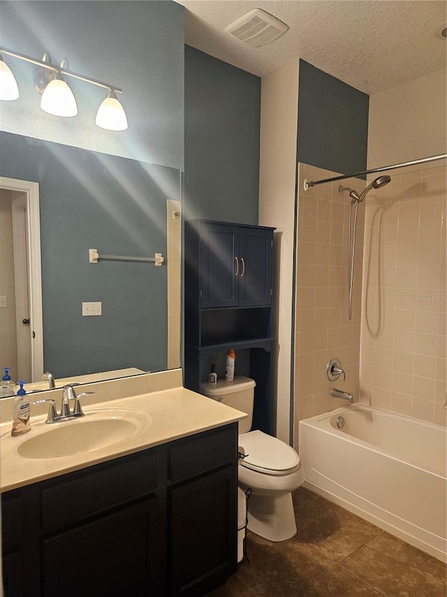 full bathroom featuring a textured ceiling, toilet, tile patterned floors, vanity, and tiled shower / bath combo