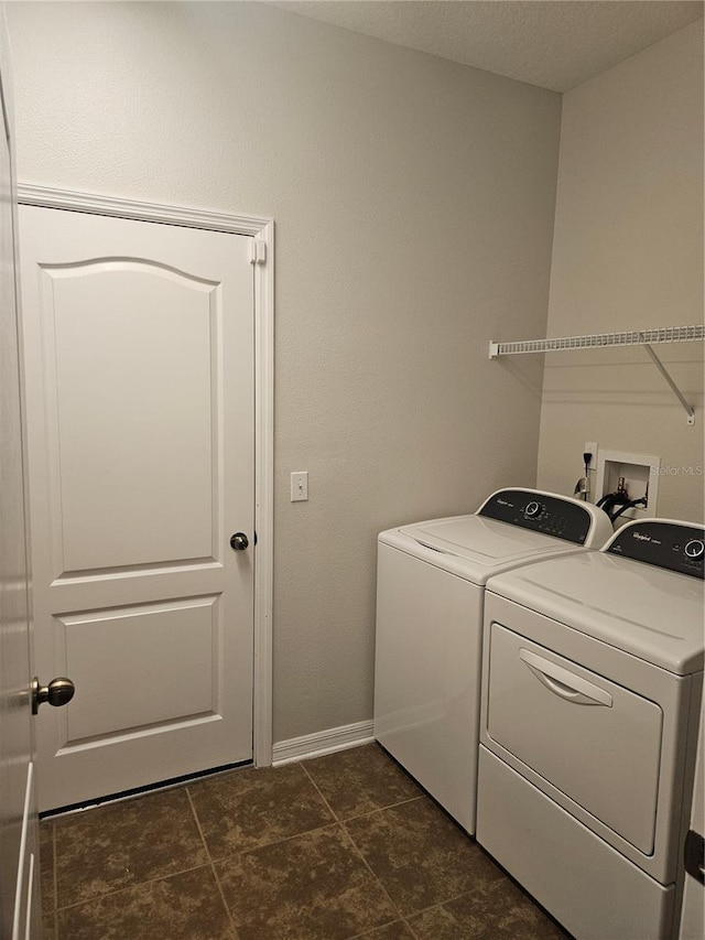 clothes washing area with washing machine and clothes dryer and dark tile patterned floors