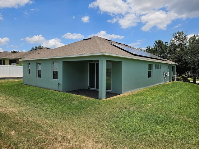 back of house featuring solar panels and a lawn