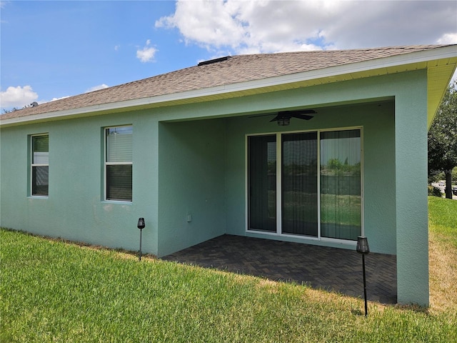 back of property featuring ceiling fan and a lawn