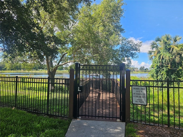 view of gate with a water view and a yard