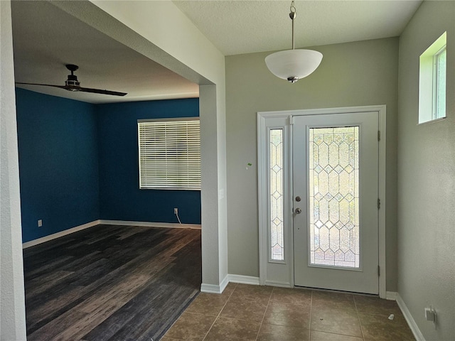 foyer entrance with a textured ceiling, dark wood-type flooring, and ceiling fan