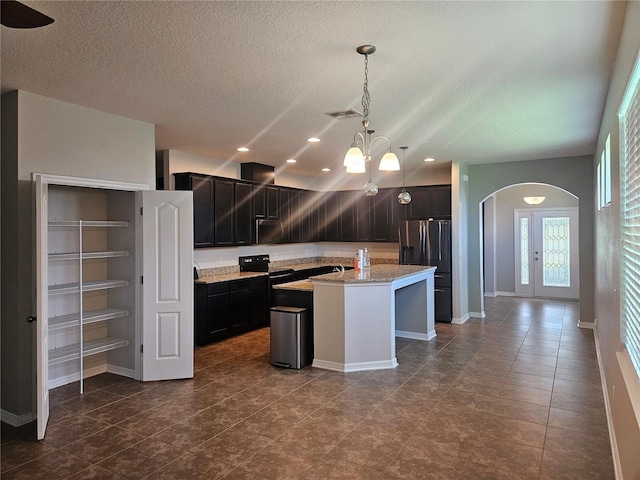 kitchen with an island with sink, a textured ceiling, electric range, hanging light fixtures, and stainless steel fridge with ice dispenser