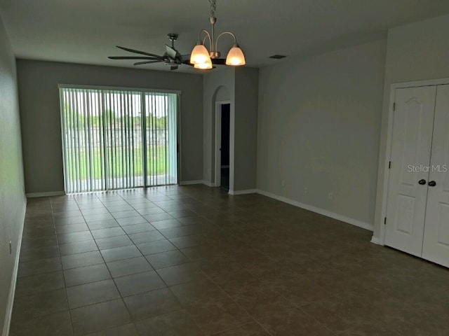 unfurnished room with ceiling fan with notable chandelier and dark tile patterned floors