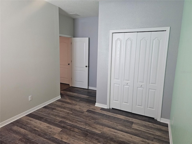 unfurnished bedroom with dark wood-type flooring and a closet