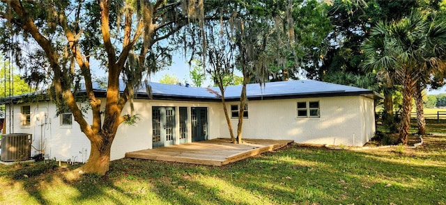 rear view of house with french doors, a yard, a deck, solar panels, and central AC unit