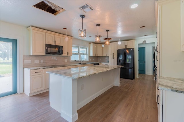 kitchen with pendant lighting, black appliances, sink, decorative backsplash, and a kitchen island