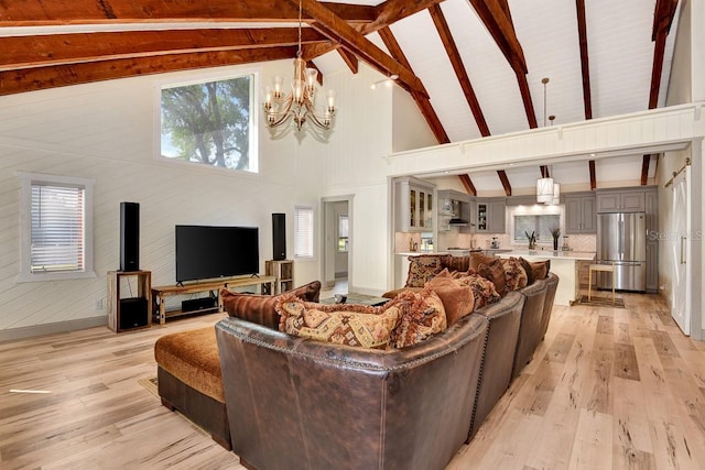 living room with beam ceiling, high vaulted ceiling, a chandelier, and light wood-type flooring