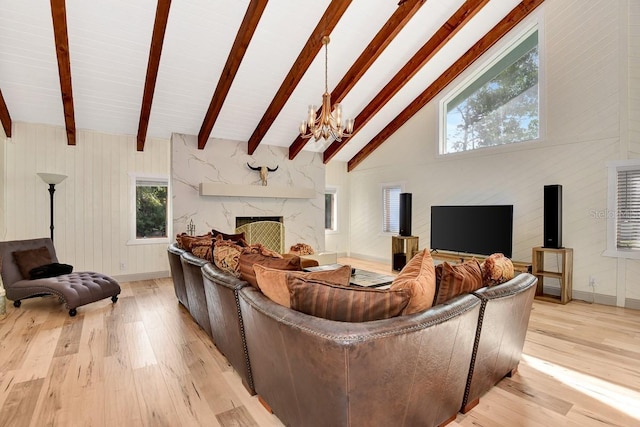 living room with high vaulted ceiling, a high end fireplace, light hardwood / wood-style floors, beamed ceiling, and a chandelier